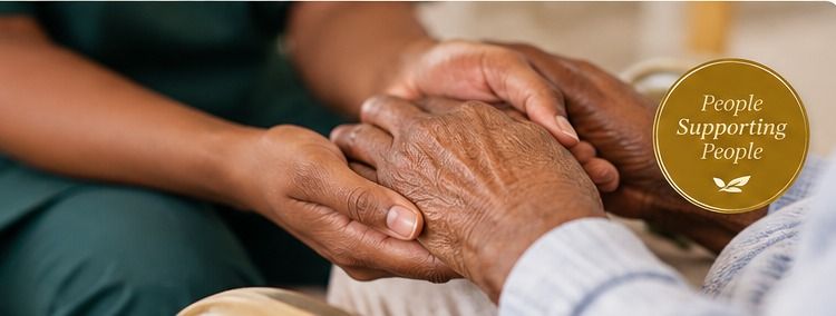 A caregiver’s hands gently holding the hands of an older adult